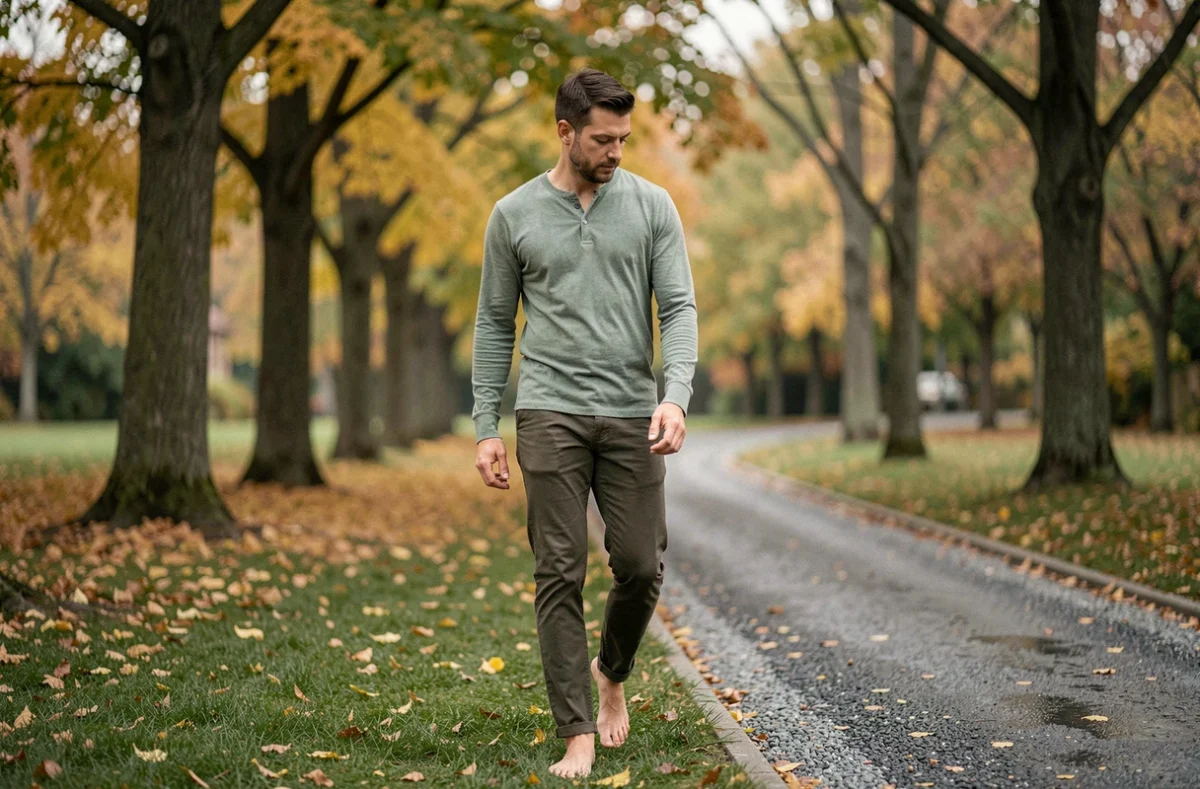 Homme se promenant pieds nus dans un parc en automne pour abaisser le cortisol et apaiser le stress chronique